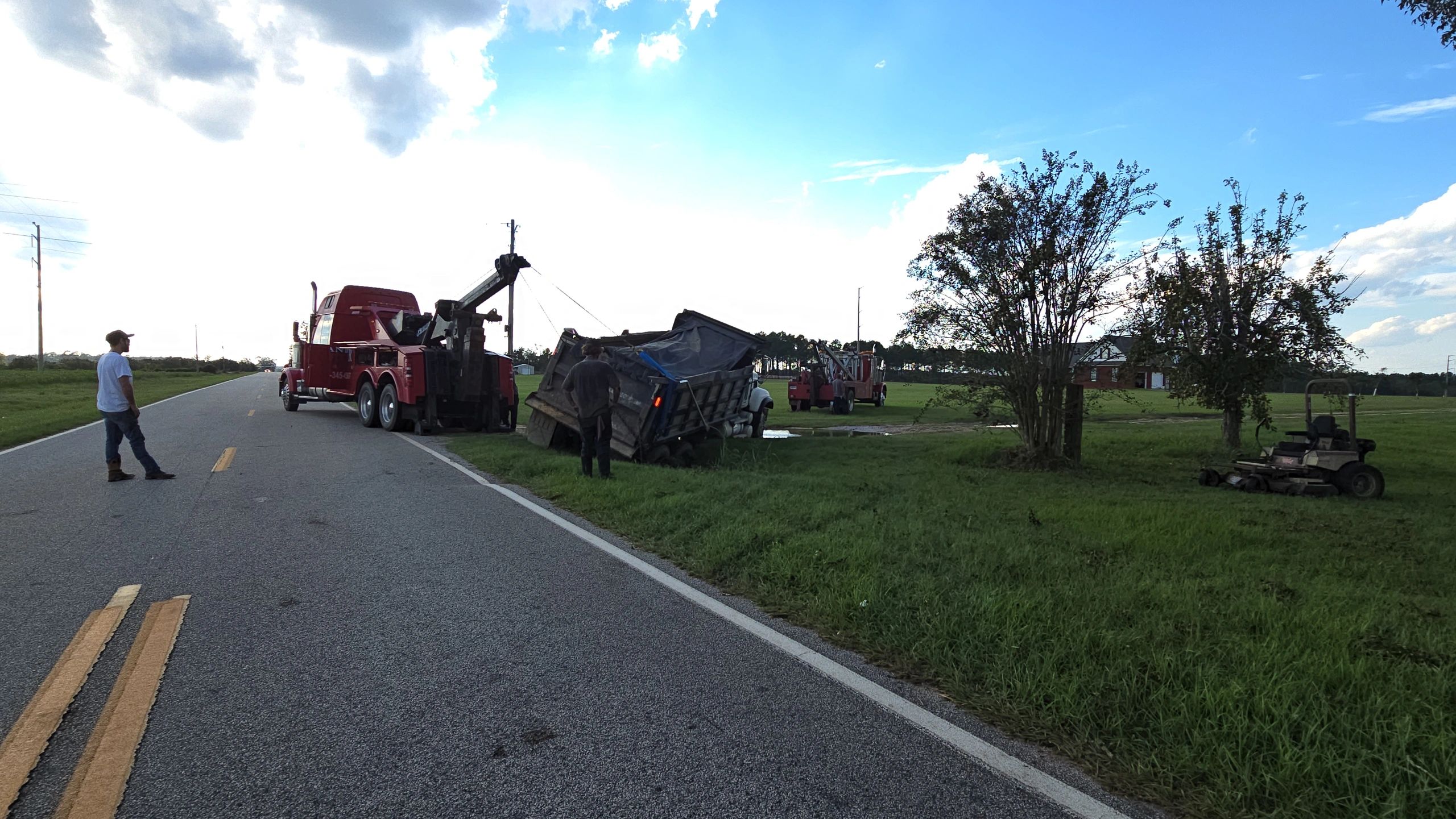 Tow trucks recovering a tipped dump truck by the roadside